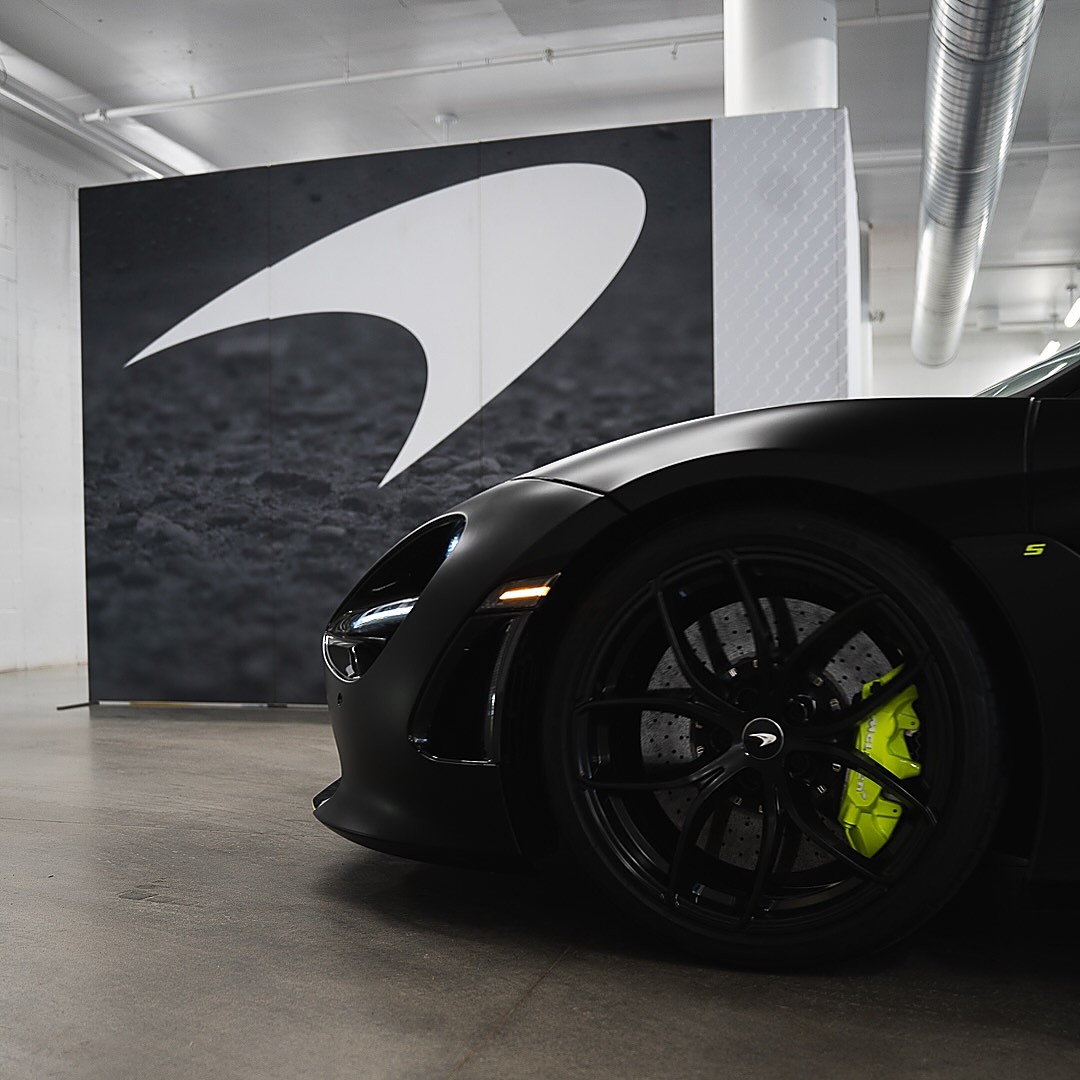 McLaren front wheel with green caliper in front of the McLaren logo