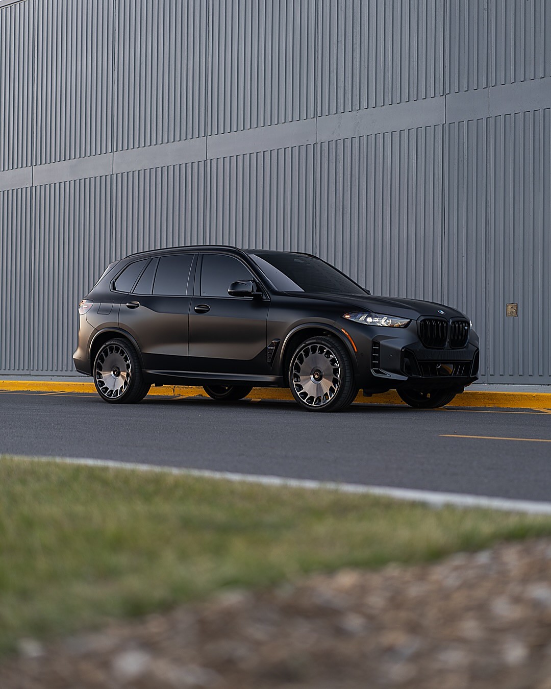 Satin BMW X5 M60i by a grey wall